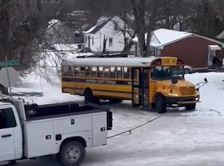 Yellow school bus stuck in heavy snow outside a house, illustrating conditions that can lead to a snow day school closure